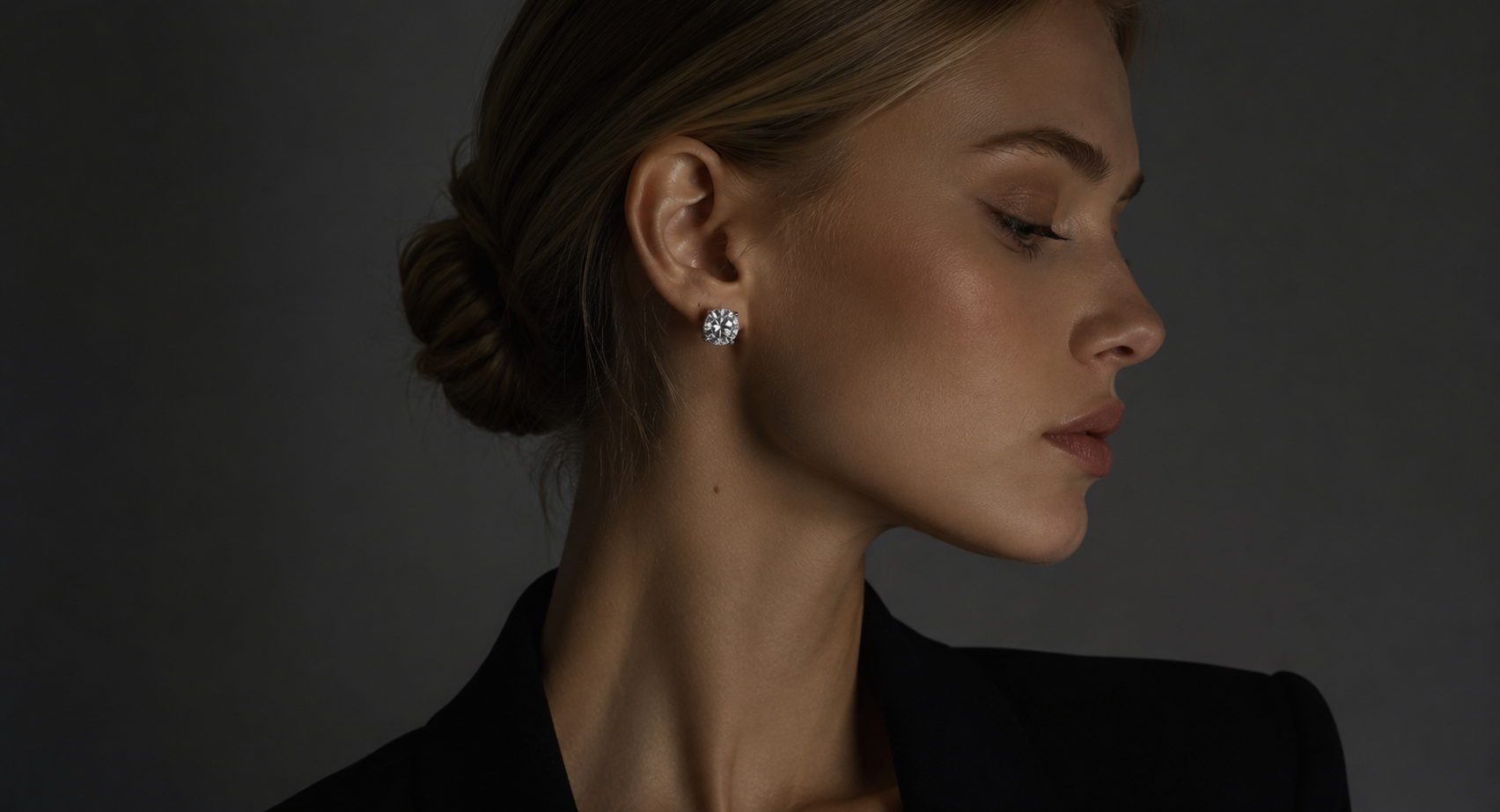 Woman wearing diamond earrings against a dark background